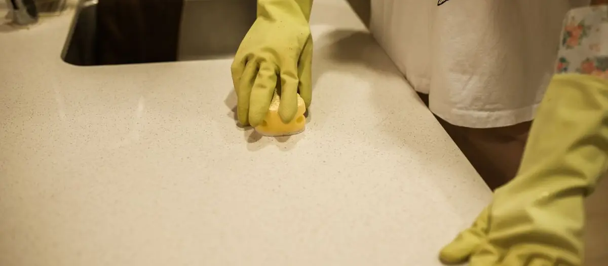 Manos con guantes limpiando una encimera