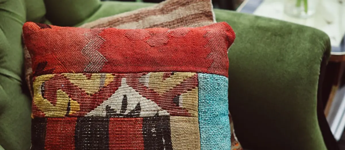 Cojín de lana tejida sobre un sillón verde