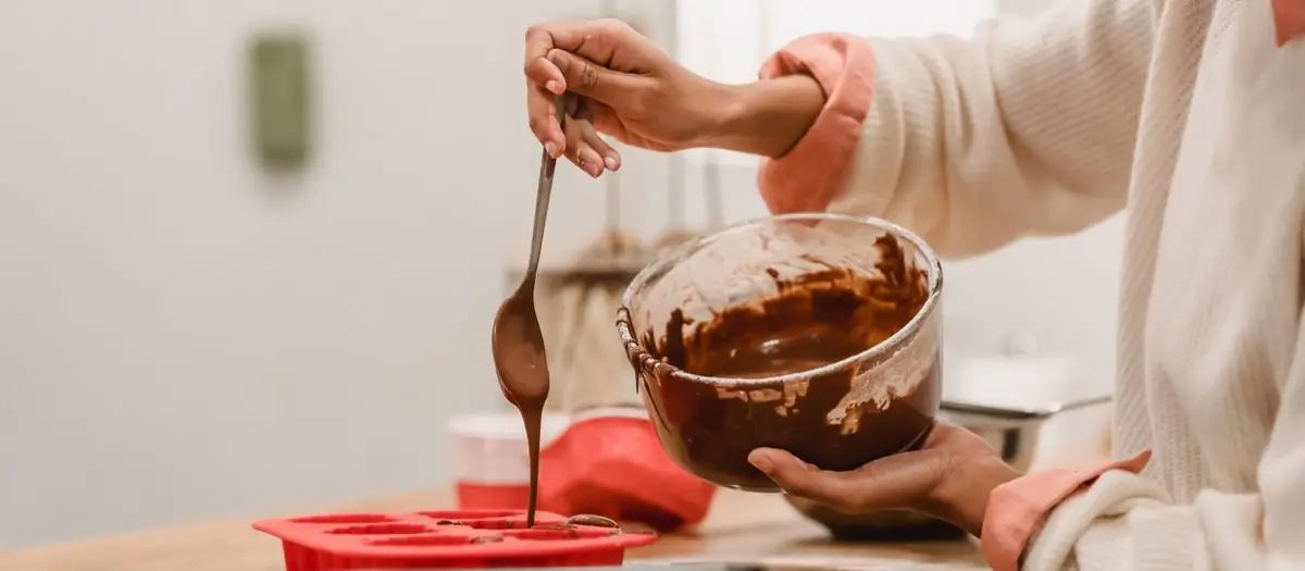 Persona vertiendo chocolate en un molde de silicona