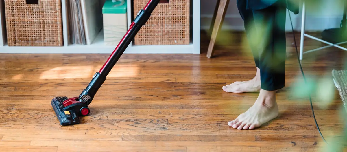 Persona pasando la aspiradora por un suelo de madera
