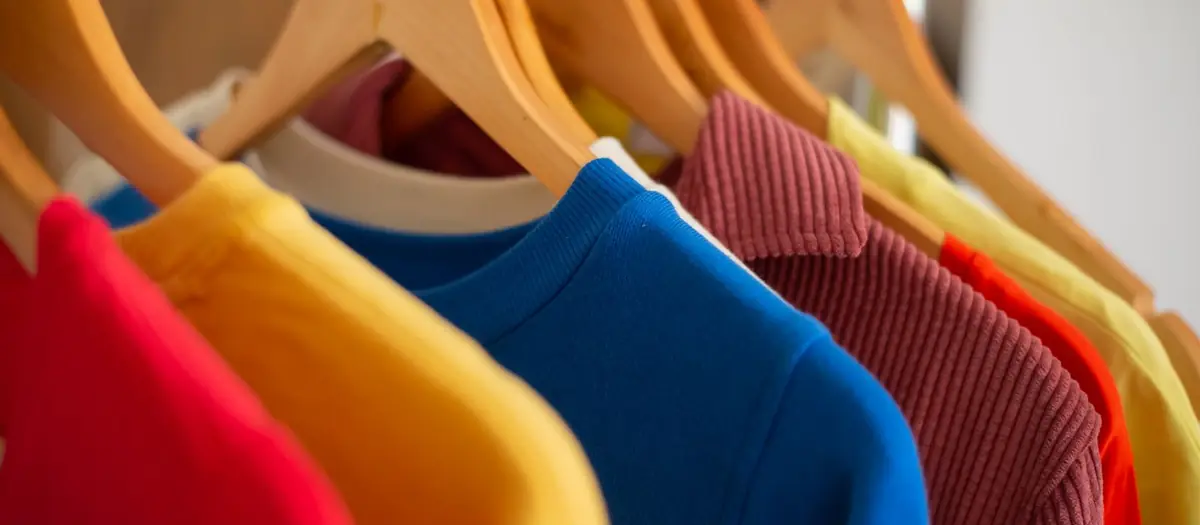 Jerséis de colores colgados en perchas de madera