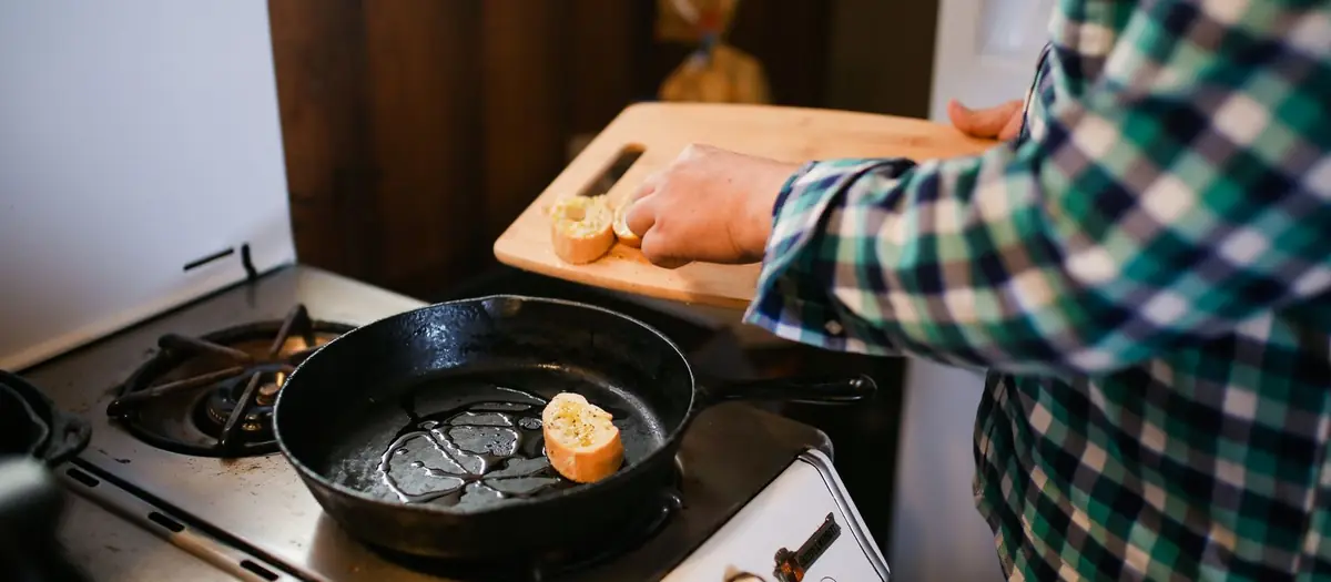 Persona cocinando con una sartén en el fuego