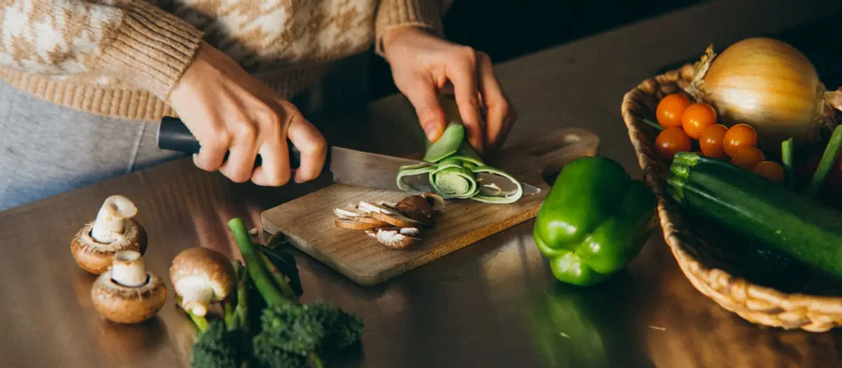 Manos cortando verduras sobre una tabla de madera