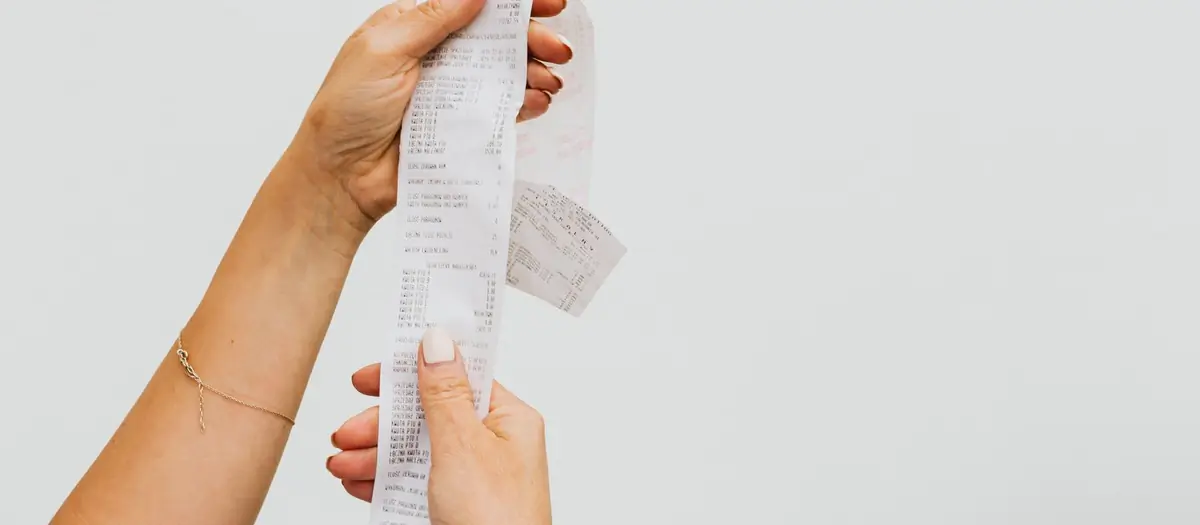 Manos sujetando un ticket de compra largo