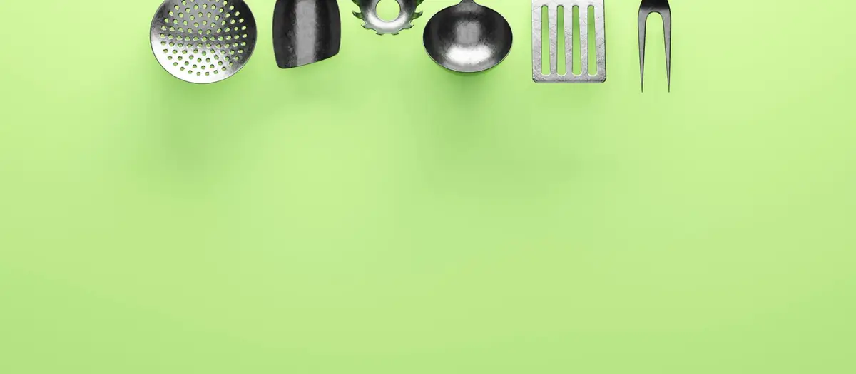 Utensilios de cocina colgados sobre fondo verde