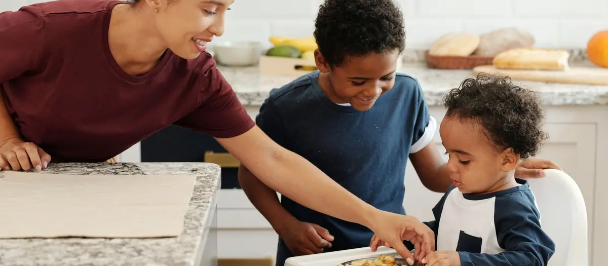 Madre poniendo un plato de comida a su hijo en la trona