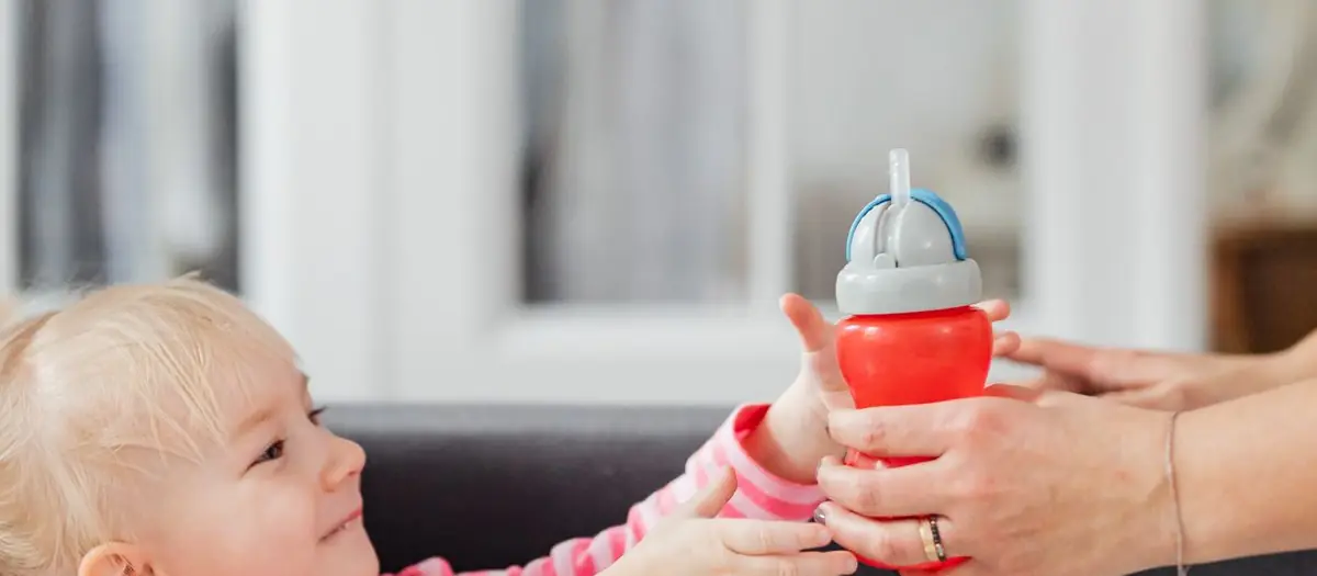 Madre dando a su hija un vaso de aprendizaje